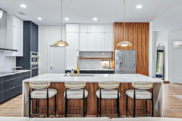 kitchen featuring appliances with stainless steel finishes, modern cabinets, a sink, tasteful backsplash, and recessed lighting