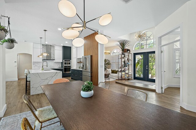 15415 Alexander Run, Jupiter, FL 33478 - dining room with light wood-style floors, baseboards, a chandelier, french doors, and arched walkways