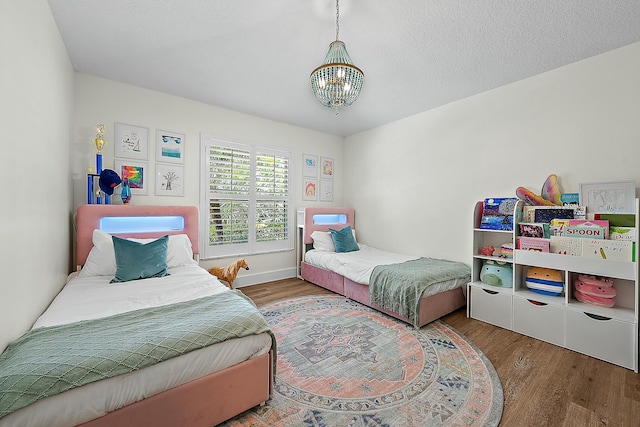 bedroom with a chandelier, wood finished floors, and baseboards