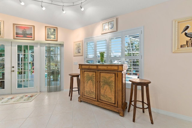 bar featuring baseboards, vaulted ceiling, and light tile patterned floors