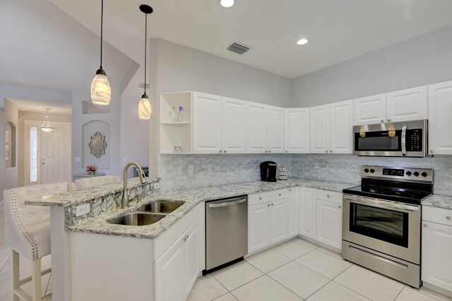 kitchen with a sink, tasteful backsplash, appliances with stainless steel finishes, and a peninsula