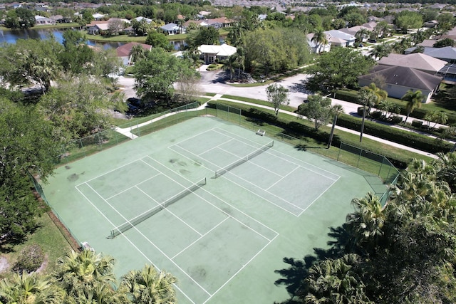 view of sport court with a residential view, a water view, and fence