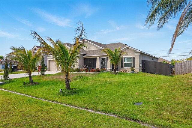 1041 SW Dartmouth Ave, Port Saint Lucie, FL 34953 - view of front facade with an attached garage, stucco siding, fence, and a front lawn