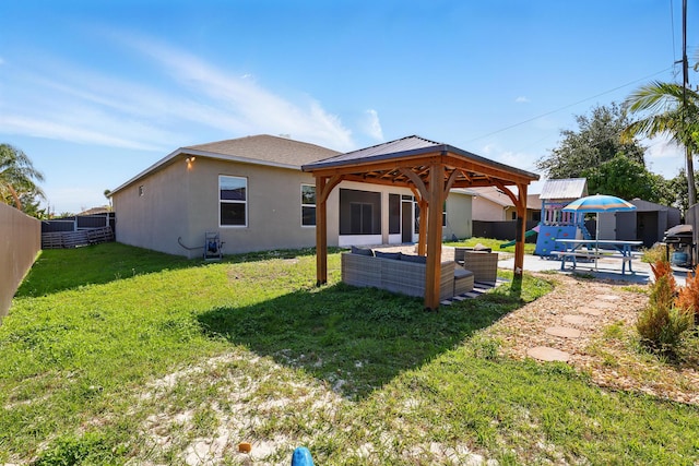 1041 SW Dartmouth Ave, Port Saint Lucie, FL 34953 - back of property featuring an outdoor living space, stucco siding, a lawn, fence, and a gazebo