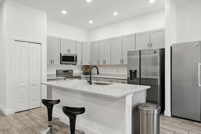 1041 SW Dartmouth Ave, Port Saint Lucie, FL 34953 - kitchen with wood finish floors, light stone counters, an island with sink, stainless steel appliances, and a sink