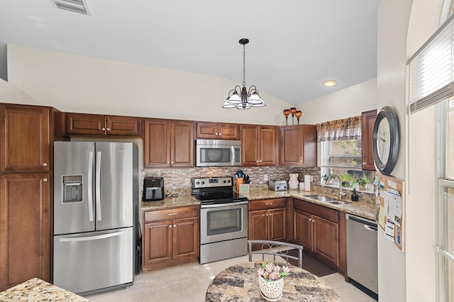 kitchen with a sink, tasteful backsplash, lofted ceiling, light stone countertops, and appliances with stainless steel finishes