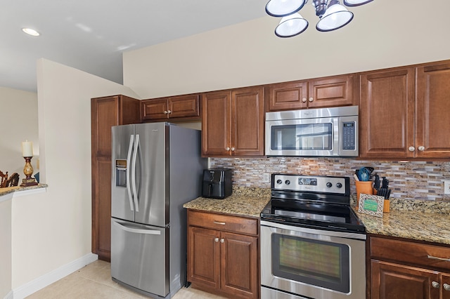 kitchen with light stone counters, decorative backsplash, stainless steel appliances, and light tile patterned floors
