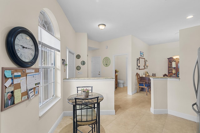 hall featuring baseboards, light tile patterned flooring, and recessed lighting
