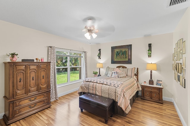 bedroom with light wood-type flooring, visible vents, a ceiling fan, and baseboards