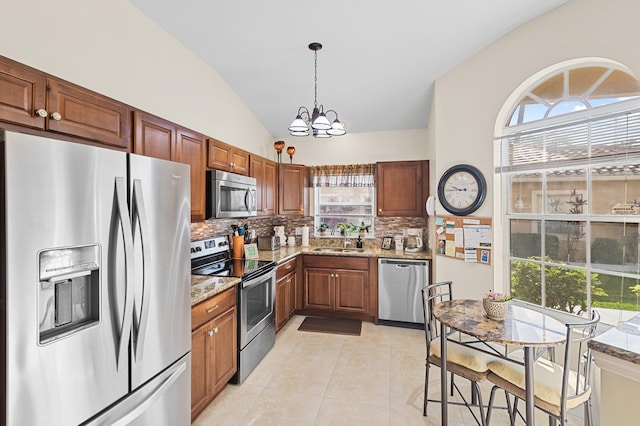 kitchen featuring stainless steel appliances, a sink, an inviting chandelier, backsplash, and lofted ceiling