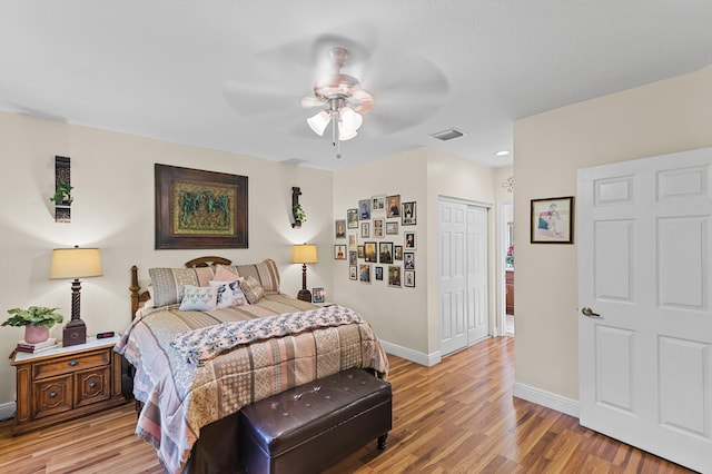 bedroom with light wood-style floors, baseboards, visible vents, and a closet