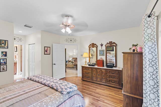 bedroom featuring ensuite bathroom, light wood-style floors, ceiling fan, baseboards, and visible vents