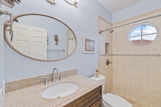 full bathroom with a tile shower, toilet, and vanity