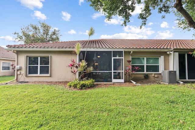 back of property with a sunroom, a yard, central air condition unit, and stucco siding