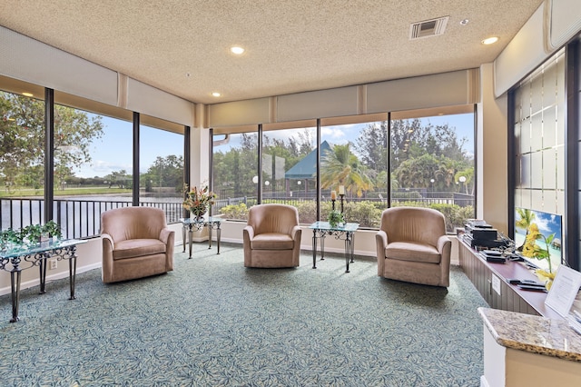 sunroom with visible vents and a water view