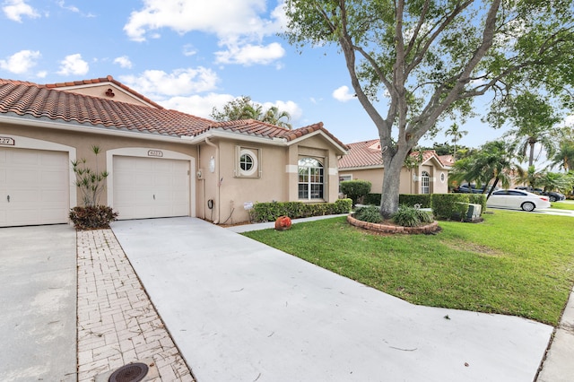 mediterranean / spanish home with a tiled roof, a front lawn, concrete driveway, a garage, and stucco siding