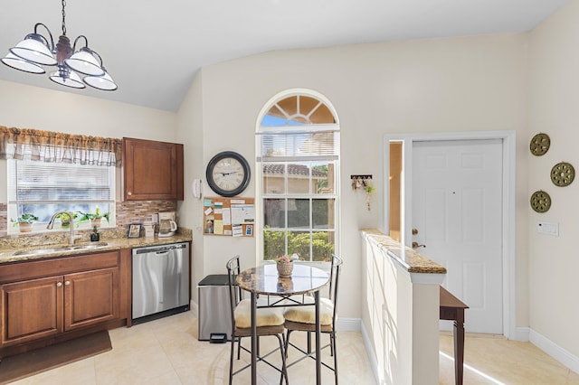 kitchen featuring stainless steel dishwasher, light stone counters, a sink, a chandelier, and light tile patterned floors