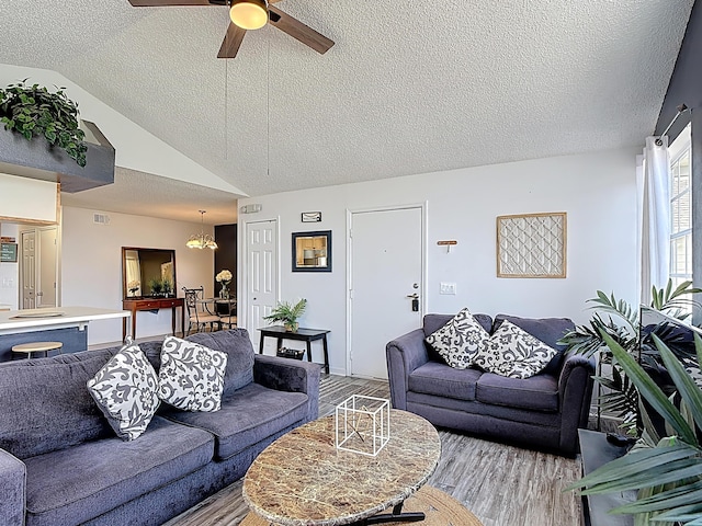 5005 Laguna Bay Cir Unit 26, Kissimmee, FL 34746 - living room featuring a textured ceiling, wood finished floors, vaulted ceiling, and ceiling fan with notable chandelier
