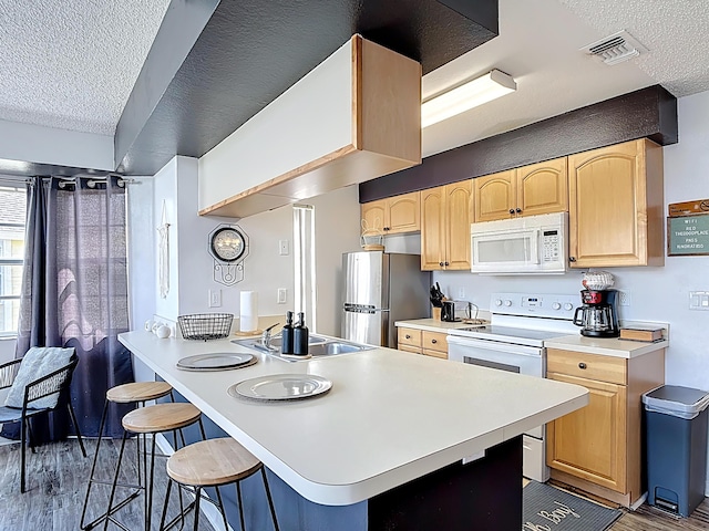 5005 Laguna Bay Cir Unit 26, Kissimmee, FL 34746 - kitchen featuring wood finished floors, white appliances, visible vents, a textured ceiling, and a kitchen breakfast bar