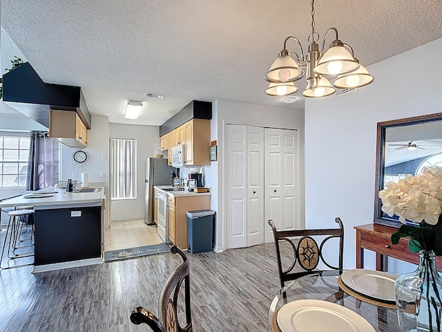 5005 Laguna Bay Cir Unit 26, Kissimmee, FL 34746 - kitchen with a textured ceiling, light countertops, light brown cabinetry, white appliances, and a notable chandelier