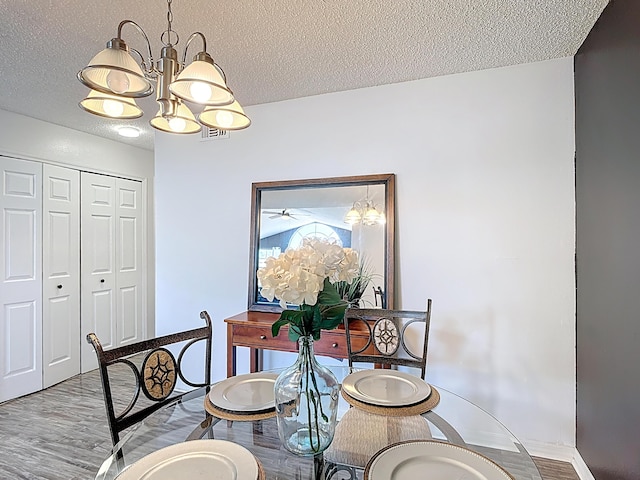 5005 Laguna Bay Cir Unit 26, Kissimmee, FL 34746 - dining room featuring an inviting chandelier, visible vents, baseboards, a textured ceiling, and wood finished floors