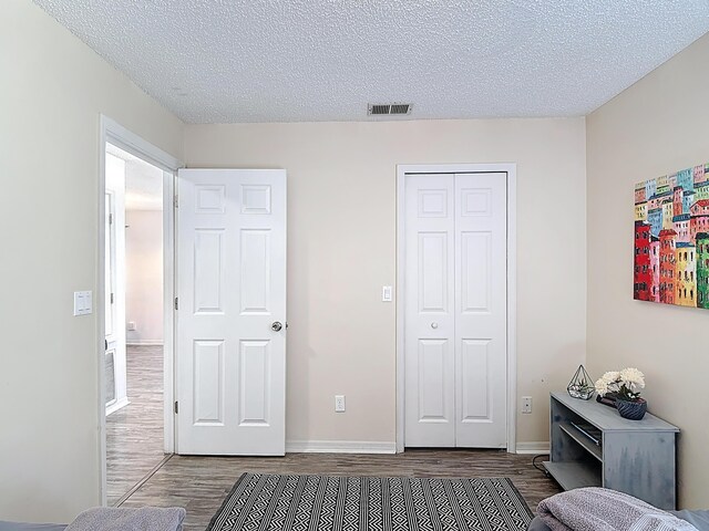 5005 Laguna Bay Cir Unit 26, Kissimmee, FL 34746 - bedroom featuring a textured ceiling, visible vents, baseboards, a closet, and wood finished floors