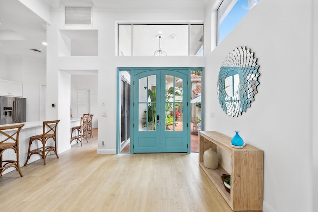 foyer featuring visible vents, light wood-style floors, french doors, and a healthy amount of sunlight