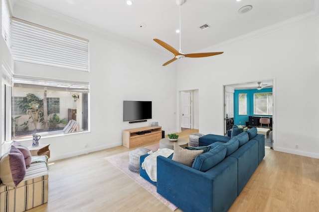 living area with visible vents, ornamental molding, and a ceiling fan