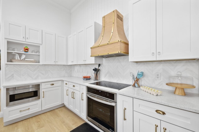 kitchen featuring crown molding, tasteful backsplash, appliances with stainless steel finishes, light wood-type flooring, and custom range hood