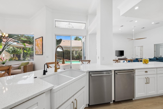 kitchen featuring open floor plan, ornamental molding, a sink, light stone counters, and dishwasher