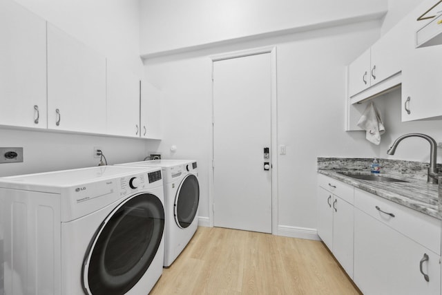 laundry room with a sink, washing machine and clothes dryer, baseboards, light wood-style floors, and cabinet space