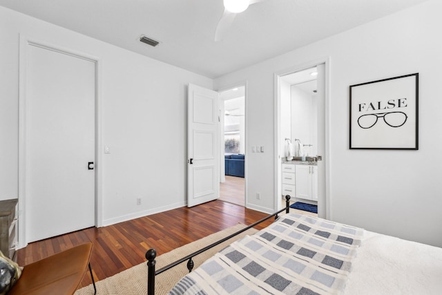 bedroom with ensuite bathroom, visible vents, baseboards, ceiling fan, and wood finished floors