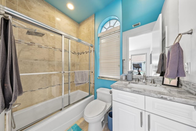 bathroom with toilet, vanity, enclosed tub / shower combo, and visible vents