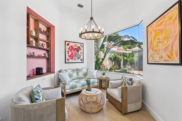sitting room featuring an inviting chandelier, ornamental molding, baseboards, visible vents, and wood finished floors