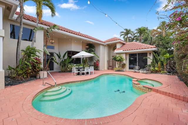 view of swimming pool featuring a pool with connected hot tub, outdoor dining area, and a patio