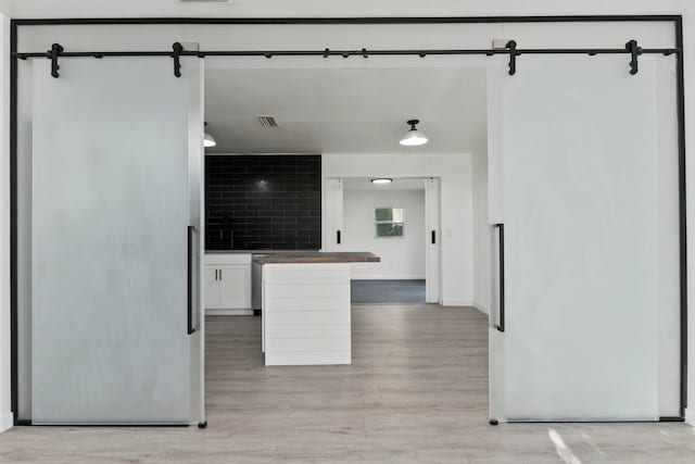 kitchen featuring baseboards, visible vents, white cabinets, and light wood-style flooring