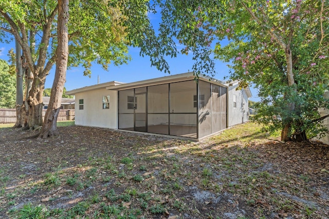 rear view of property featuring a sunroom and fence