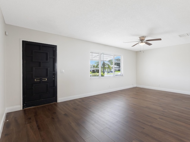 interior space with dark wood-type flooring, baseboards, ceiling fan, and visible vents
