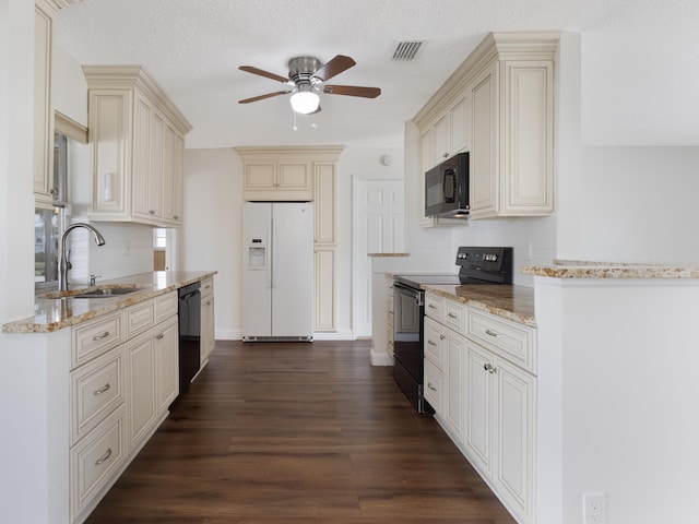 kitchen featuring visible vents, black appliances, cream cabinetry, and a sink