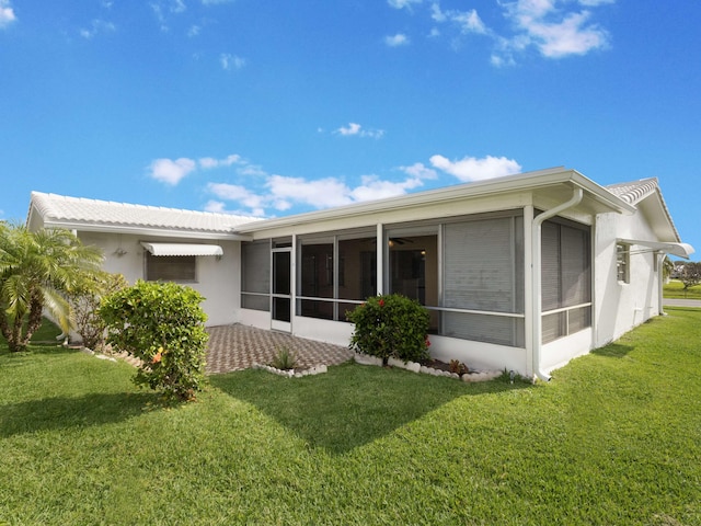 back of property with a lawn, stucco siding, and a sunroom