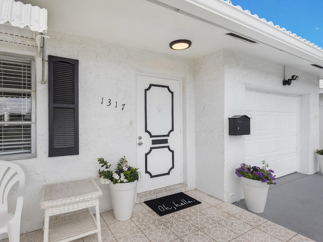 entrance to property with visible vents and stucco siding