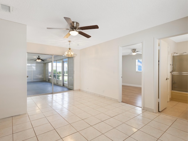 empty room with light tile patterned flooring, ceiling fan, and visible vents