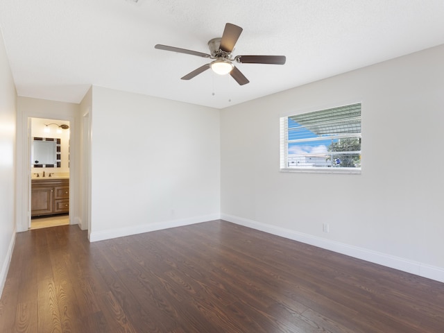 spare room with dark wood-style floors, ceiling fan, baseboards, and a sink