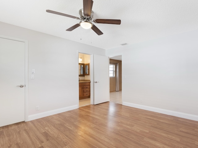 interior space with baseboards, visible vents, light wood-style floors, and a ceiling fan