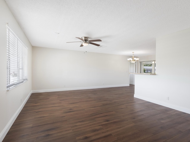 unfurnished room with ceiling fan with notable chandelier, plenty of natural light, and dark wood-style floors