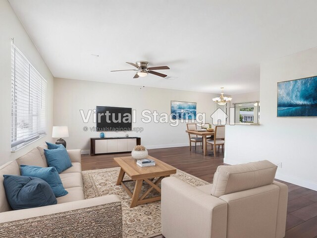 living area with dark wood-style floors, ceiling fan with notable chandelier, and a wealth of natural light