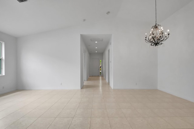empty room with light tile patterned flooring, a notable chandelier, baseboards, and a towering ceiling