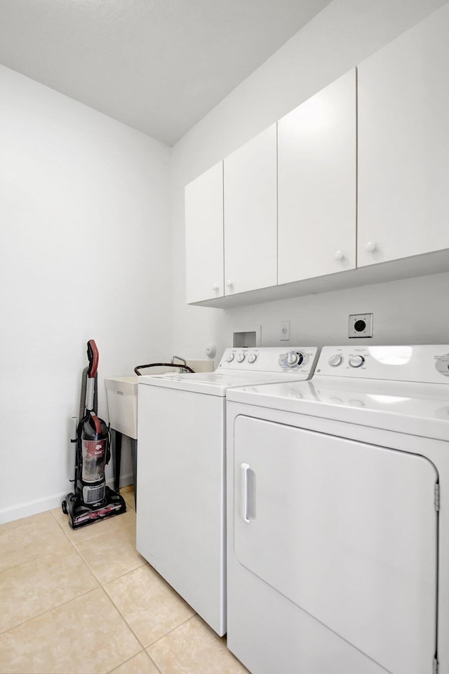 laundry room with cabinet space, light tile patterned floors, washing machine and clothes dryer, and baseboards