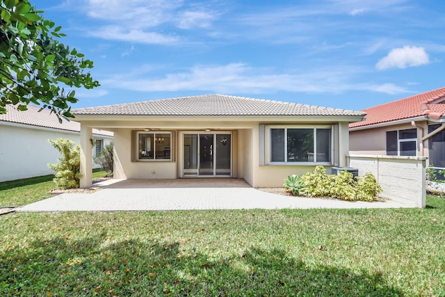 back of property featuring a tiled roof, a yard, a ceiling fan, a patio, and stucco siding