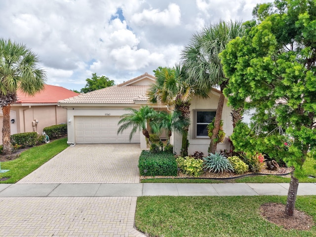 view of front of house with a tiled roof, stucco siding, a front yard, an attached garage, and driveway